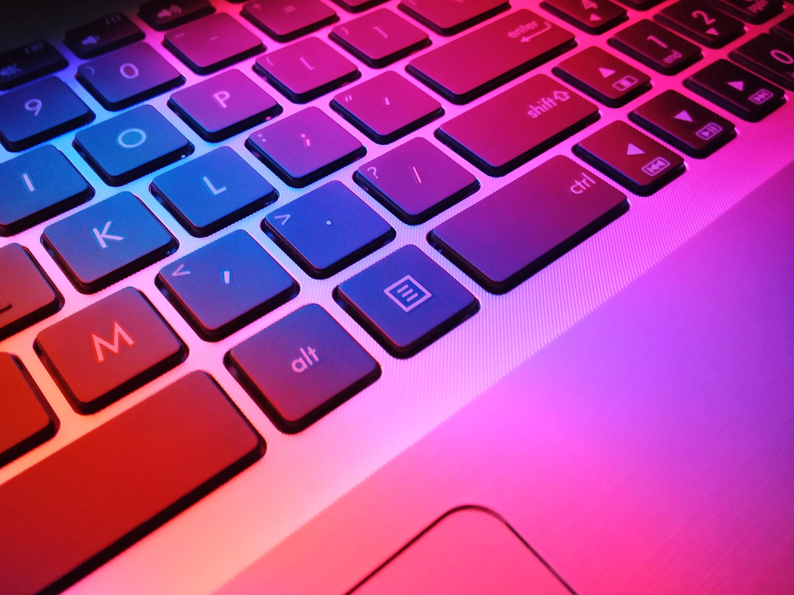 A computer keyboard is illuminated with unnatural glowing colors