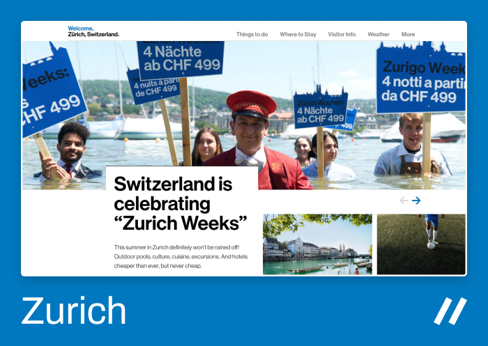 Promotional image for "Zurich Weeks" in Switzerland. A group of smiling people stands waist-deep in Lake Zurich, holding blue signs that advertise “4 Nächte ab CHF 499” (4 nights from CHF 499) in multiple languages. In the center, a man dressed as a hotel concierge in a red uniform smiles at the camera. The background features boats and green hills under a clear sky. The text on the website reads: “Switzerland is celebrating ‘Zurich Weeks’ – Outdoor pools, culture, cuisine, excursions, and affordable hotels