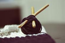 Brown yarn roll with two brown crochet hooks on top of white surface.