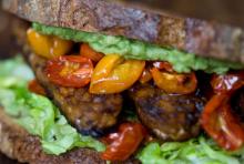 Sandwich with toast, lettuce, roasted tomatoes, and tempeh.